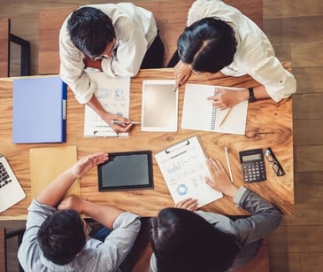 Aerial view of four people talking over paperwork.