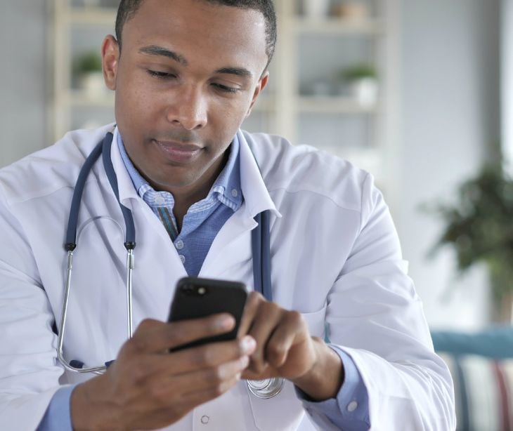 provider in white coat using cellphone