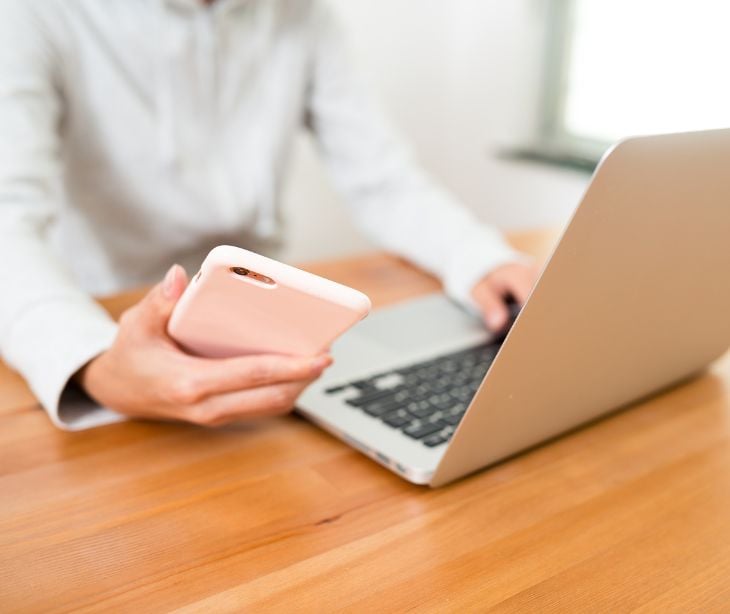 person using smartphone and laptop