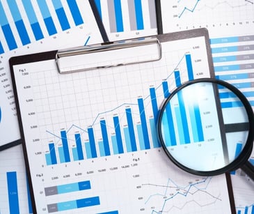 Image of printed bar graphs and magnifying glass. 