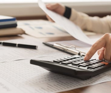 hand with calculator and paperwork on desk