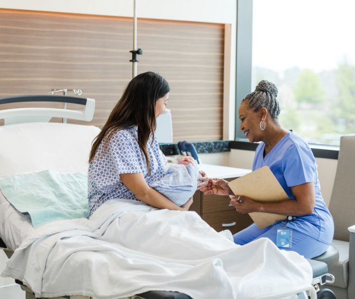 midwife with new mother and baby at hospital