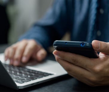 hands on laptop holding smartphone