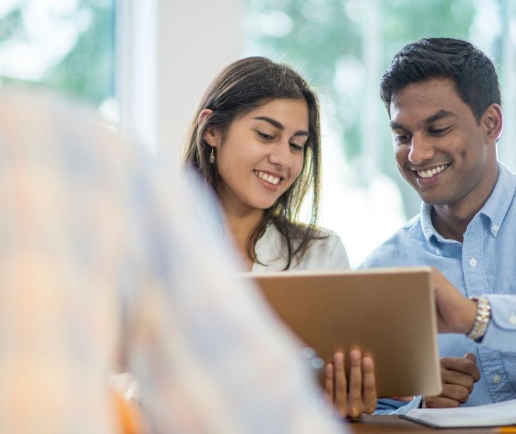 man and woman smiling at a tablet