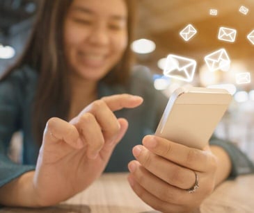 woman on smartphone with floating email icons