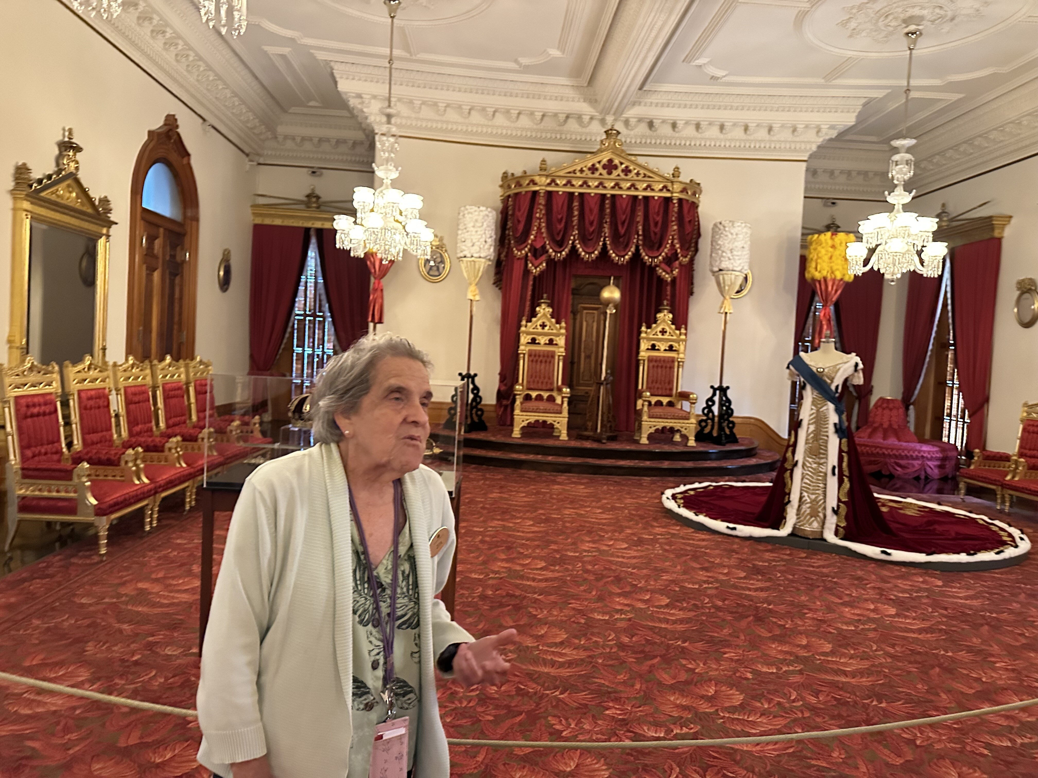 Zita Cup Choy explaining how the kapu stick, seen in the background between the two royal chairs, was built