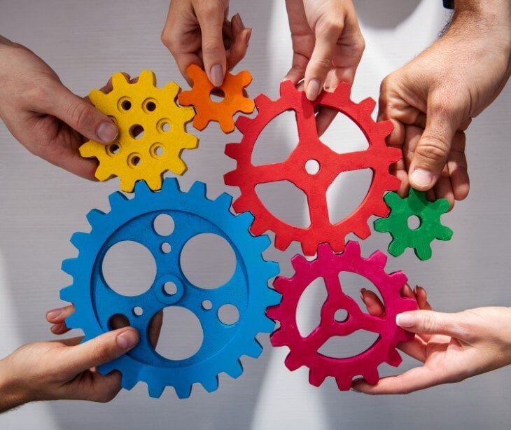 six hands holding multicolored gears