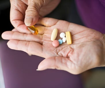 Image of someone holding several medications. 