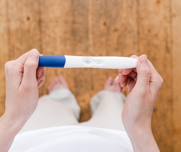 Image of someone holding a pregnancy test. 