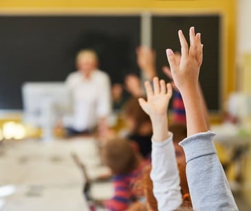 students raising hand in classroom