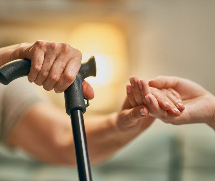 Image of individual helping another individual with a cane. 