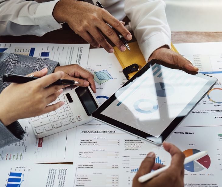 professionals working on a tablet, calculator and documents