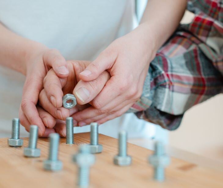 hands helping other hands with bolts and nuts